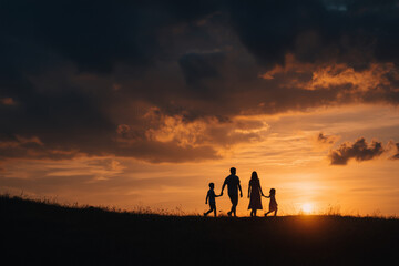 Fototapeta premium Silhouetted family walking hand in hand at sunset under dramatic orange and dark blue sky