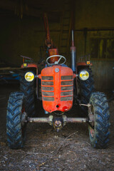 un tracteur vintage orange dans une grange