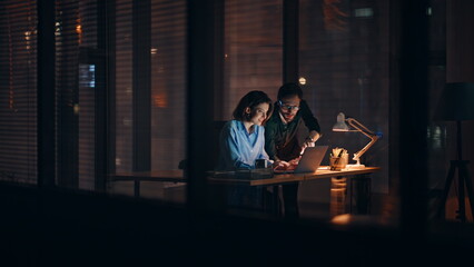 Professional team working late watching laptop at office desk late evening.  © stockbusters