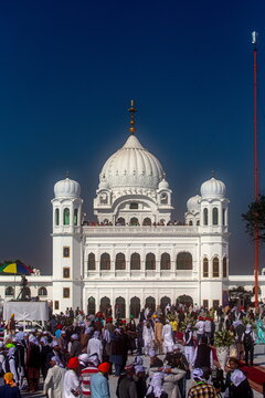 Kartarpur, Pakistan - 09 November 2019: View of the gleaming white Kartarpur Gurudwara stands majestically against the deep blue sky, bustling with devotees below.