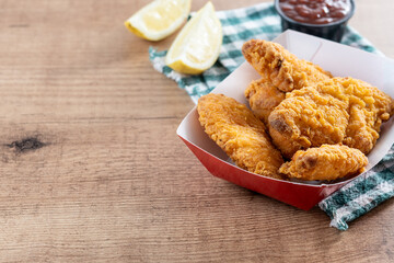Crispy fried chicken tenders on wooden table. Copy space