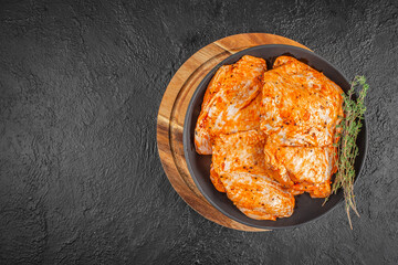 Raw marinated turkey fillet with spices and herbs on black plate. top view. copy space