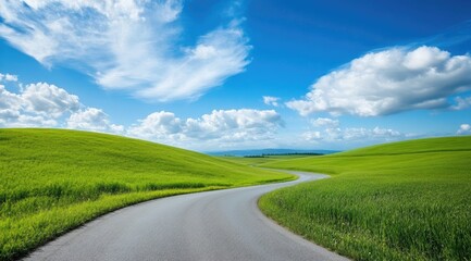 Fototapeta premium Winding road through green hills under a bright sky