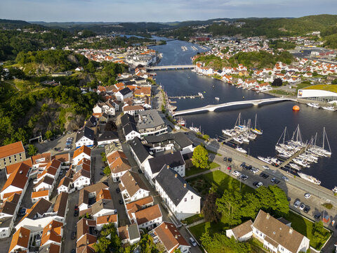 Aerial view of the charming town nestled along the Mandal River, where vibrant terracotta roofs meet the deep blues of the water, Mandal, Agder, Norway.