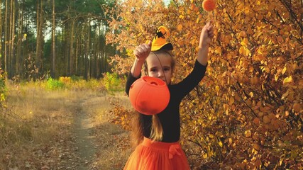 Halloween kids going to collect candy. Trick-or-treating. Child in carnival costume witch outdoors. Celebrate halloween. Girl in autumn forest smiling and holding of sweets candy - Powered by Adobe