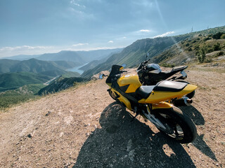 Obraz premium Scenic mountain view with motorcycles parked by the river on a sunny day