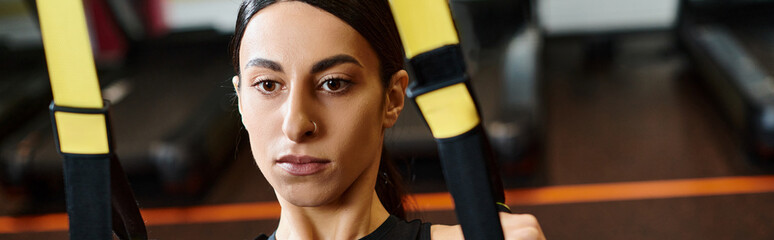 Focused female athlete engaging in suspension training at the gym during daylight hours