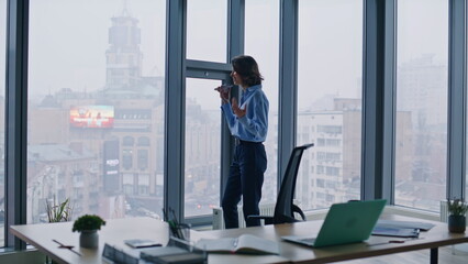 Businesswoman recording audio message at cellphone walking contemporary office. 