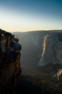 Stunning sunset view from a famous overlook in Yosemite National Park, California, USA, with a lone figure standing on a rock, admiring the vast valley and granite cliffs.