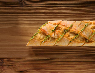 Baguette mit Kraeuterbutter angeschnitten auf rustikalem Holzfond, Brot, Kräuterbutter, Kross, 
