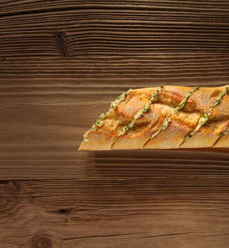 Kr&auml;uterbutter Baguette auf rustikalem Fond angeschnitten