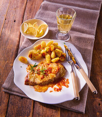 Schnitzel mit Gnochi und Weisswein auf weissem Teller mit Besteck, Italien, Zitronenschnitze, 
