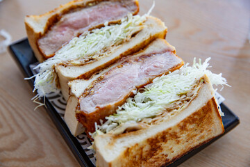 Close-up of Japanese pork cutlet sandwich showing thick pork katsu with crispy coating and finely shredded cabbage between toasted bread slices
