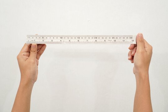Women Hand holding a stainless steel ruler on isolated white background. Precision measuring tool for length and drawing. Close up
