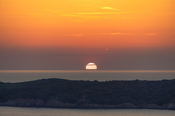 Sun half hidden by horizon at sunset, France, Corsica, Carg&egrave;se, 18 June 2025