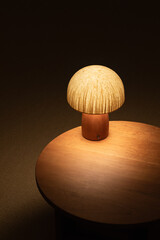 Light bulb on a wooden table. A handmade mushroom lamp sits on a round cherrywood table. Interior mood. Zen-inspired interior mood.