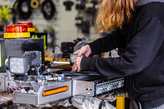 Young male mechanic assembling light bar component in industrial workshop