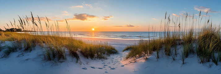 Golden sun setting over the ocean viewed through grassy dunes on a white sand beach, creating a peaceful and serene coastal scene.