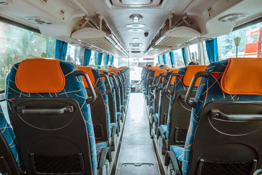 rows empty seats with orange headrests fill interior well-maintained bus. blue curtains line windows, enhancing atmosphere quiet travel experience. close up.