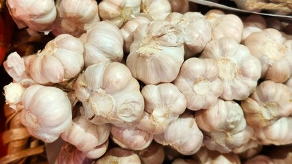 Close-up of a pile of fresh garlic bulbs with papery skins, showing clusters of cloves ready for cooking or sale.