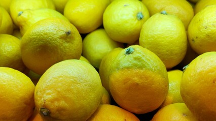 Close-up of a pile of fresh bright yellow lemons with textured rinds filling the frame.