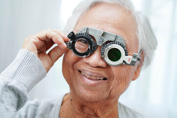 Asian senior woman wearing ophthalmic vision eye test and using optical trial frame.