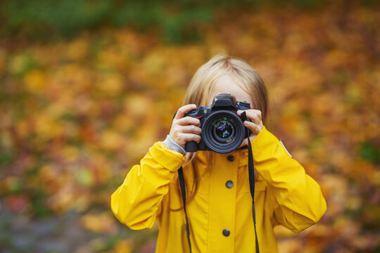 Smiling little girl Taking Pictures by DSLR camera.