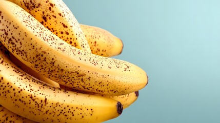 Bunch of ripe yellow bananas with brown spots on a light blue background fruit