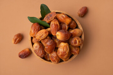 Delicious dried dates in wooden bowl on brown background flat lay top view. Oriental fruit, date palm fruit, natural sweet dessert. Organic healthy snack, food background