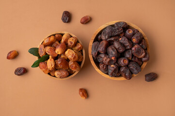 Delicious dried dates of different varieties in wooden bowls on brown background top view. Oriental fruit, date palm fruit, natural sweet dessert. Organic healthy snack, food background