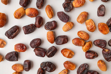 Delicious dried dates of different varieties scattered on gray background flat lay top view. Sweet oriental organic dessert, date palm fruit, healthy snack. Food background