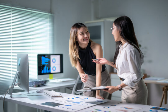 Asian businesswomen discussing charts and data analysis in modern office
