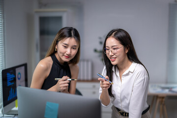 Asian businesswomen discussing work using computer in office
