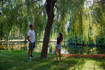 Fototapeta premium Father and daughter in the park on a summer morning spending time together enjoying nature.