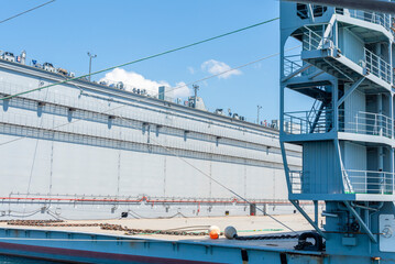 Fototapeta premium Cargo vessel loading operations at the port during daytime in a bustling maritime environment