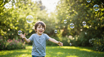 Happy boy playing with soap bubbles in a sunny garden during summer