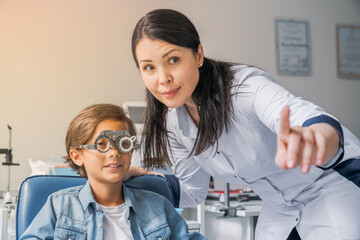 Eye examination. Children's doctor putting trial frame on little boy in clinic. Selection frame goggles eyesight vision lenses in optic ophthalmological clinic hospital