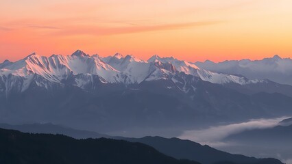 Majestic mountain range at sunrise with soft pink and orange hues over snowy peaks and misty valleys.