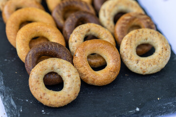 Freshly baked mini bagels on a dark background. Top view. Pretzels in the form of a ring close-up. Small bread circle biscuit. Bowls with different types of bagels.