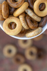 Freshly baked mini bagels on a dark background. Top view. Pretzels in the form of a ring close-up. Small bread circle biscuit. Bowls with different types of bagels.