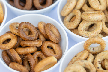 Freshly baked mini bagels on a dark background. Top view. Pretzels in the form of a ring close-up. Small bread circle biscuit. Bowls with different types of bagels.