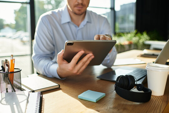 Handsome young businessman engaged in productive work at modern office desk setting