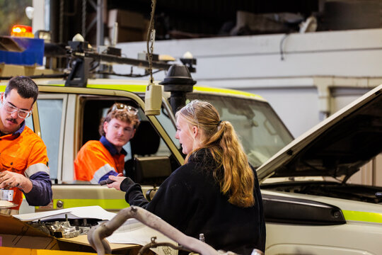Mechanics having conversation beside mining fleet vehicle inside workshop