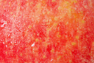 Red apple texture as a background with water drops.