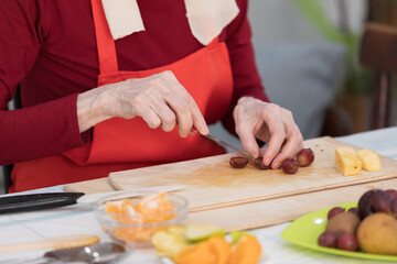 Elderly woman preparing fruit salad at home in the living room
