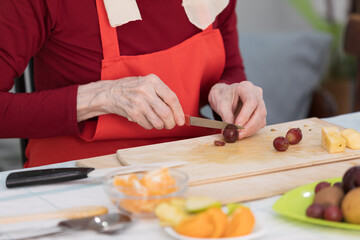 Elderly woman preparing fruit salad at home in the living room