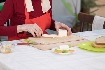 Elderly woman preparing fruit salad at home in the living room
