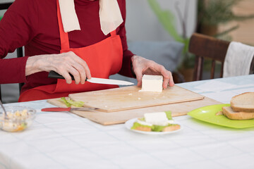 Elderly woman preparing a butter sandwich