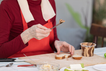 Elderly woman preparing fruit salad at home in the living room