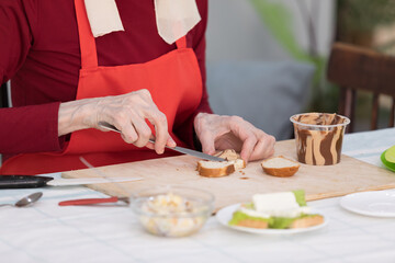 Elderly woman preparing a butter sandwich